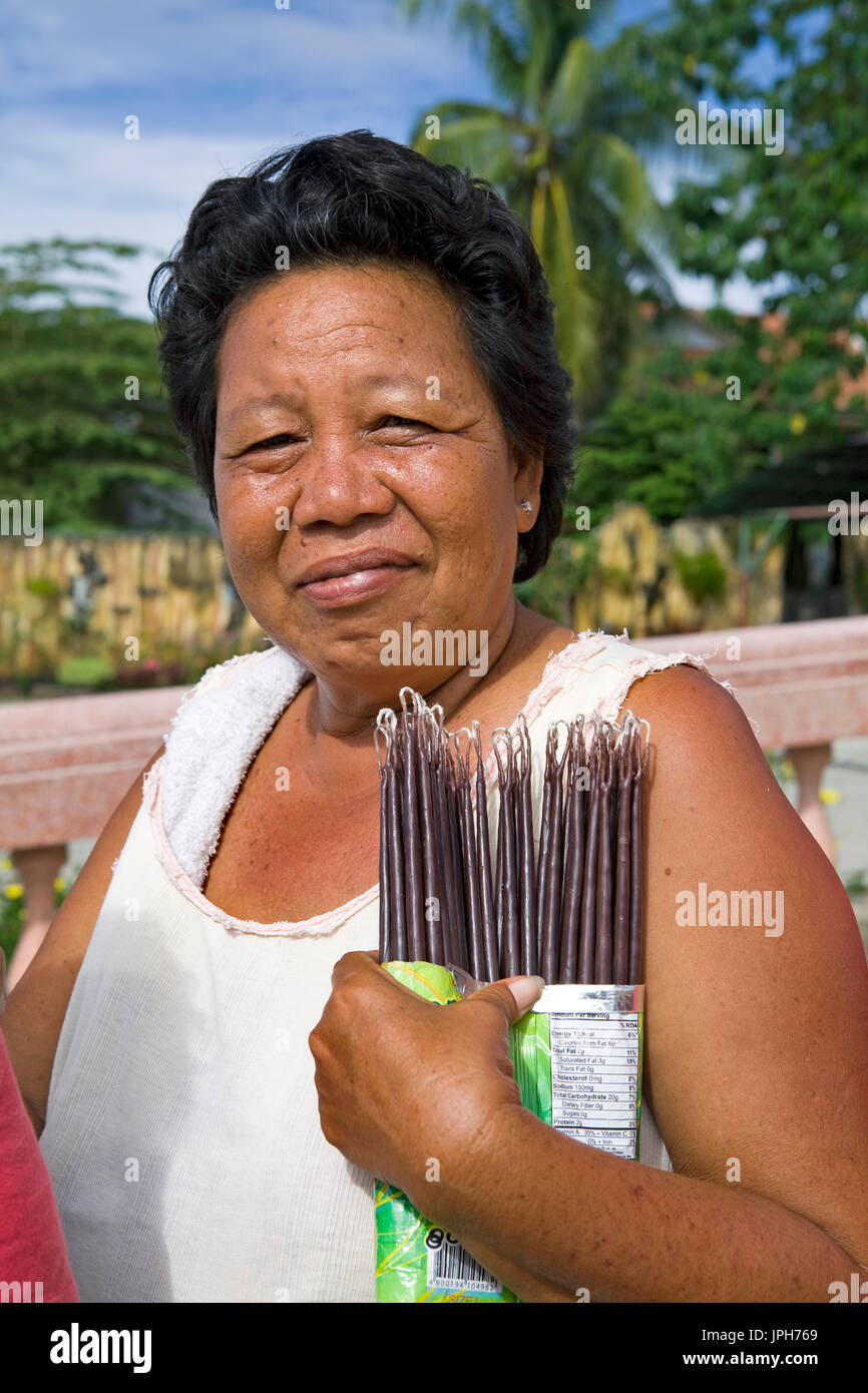 Middle-aged Filipino woman sells votive candles near the Cathedral and Shrine of San Vincent Ferrer, in Bogo City, Cebu Island, Philippines. Stock Photo