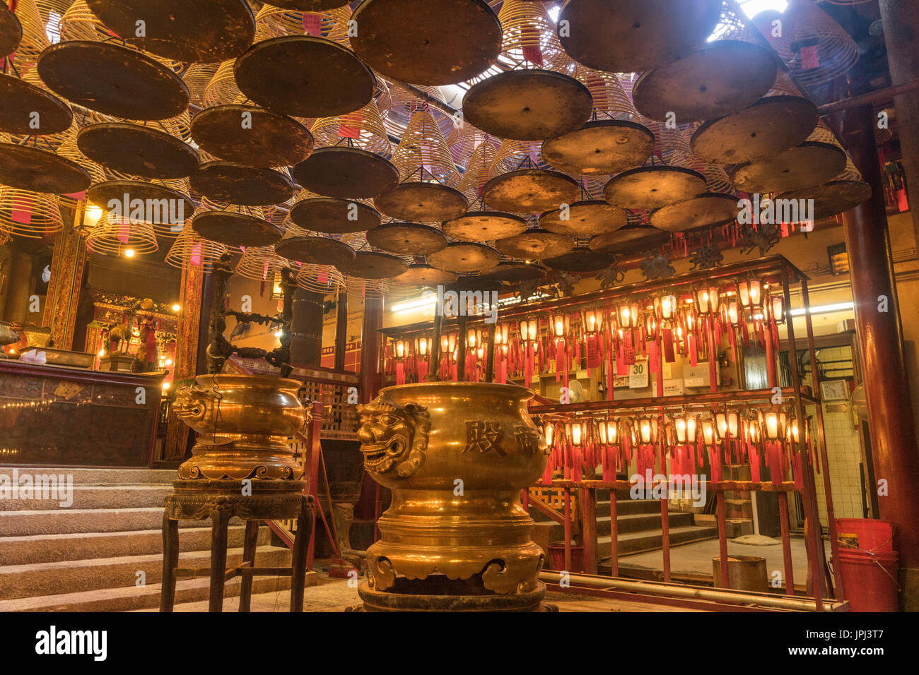 Gold urns and incense coils burning inside Man Mo Temple in Hong Kong Stock Photo
