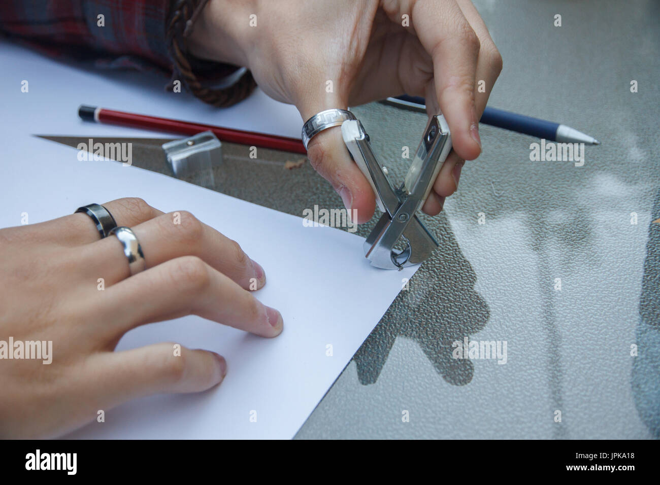 Photo of close up of a hands removing a staple from some documents with a staple remover Stock