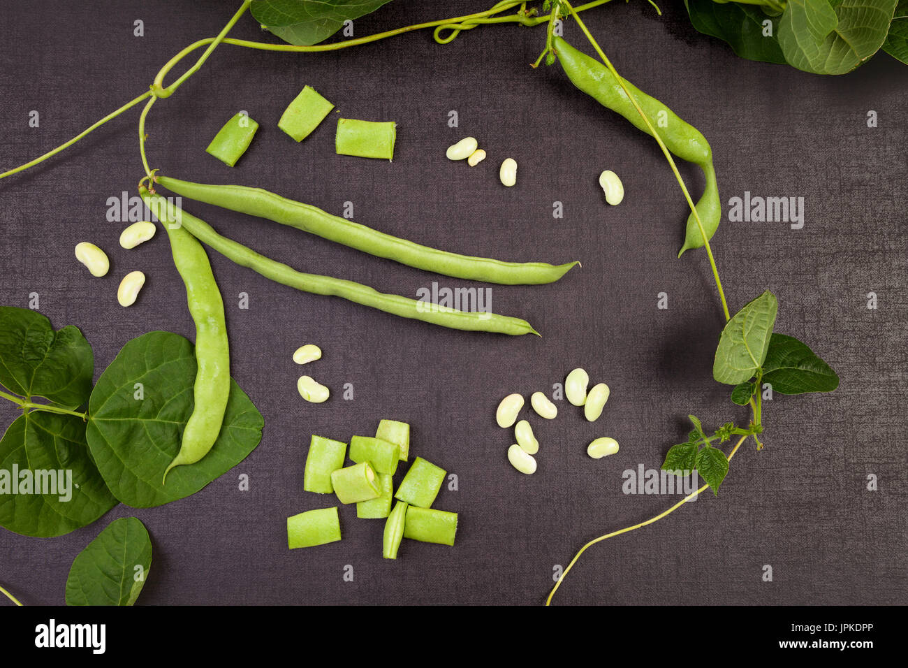 Raw green string beans, whole and sliced, black surface. Healthy