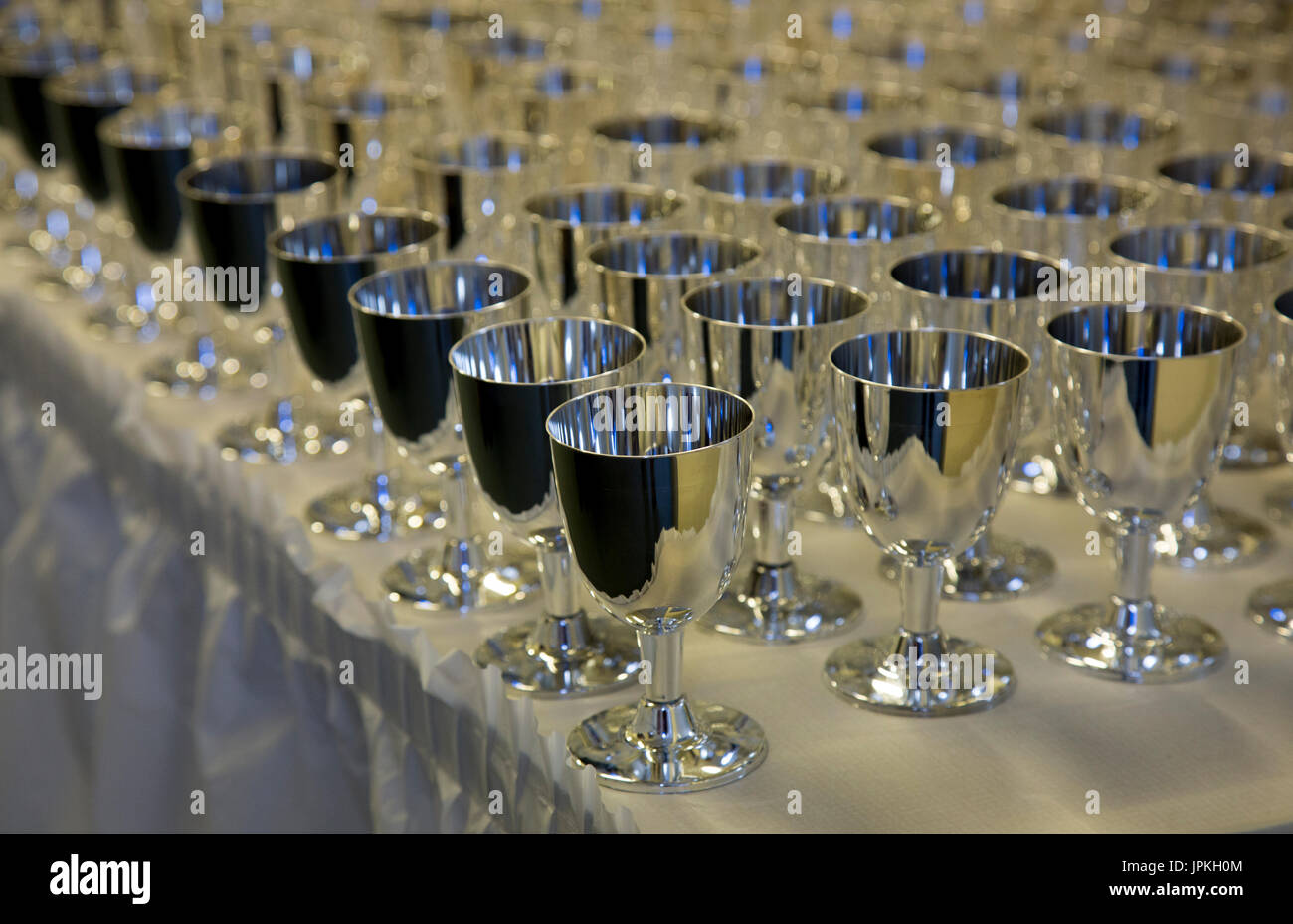 Rows of silver champagne goblets on a table with a white tablecloth to celebrate high school prom Stock Photo