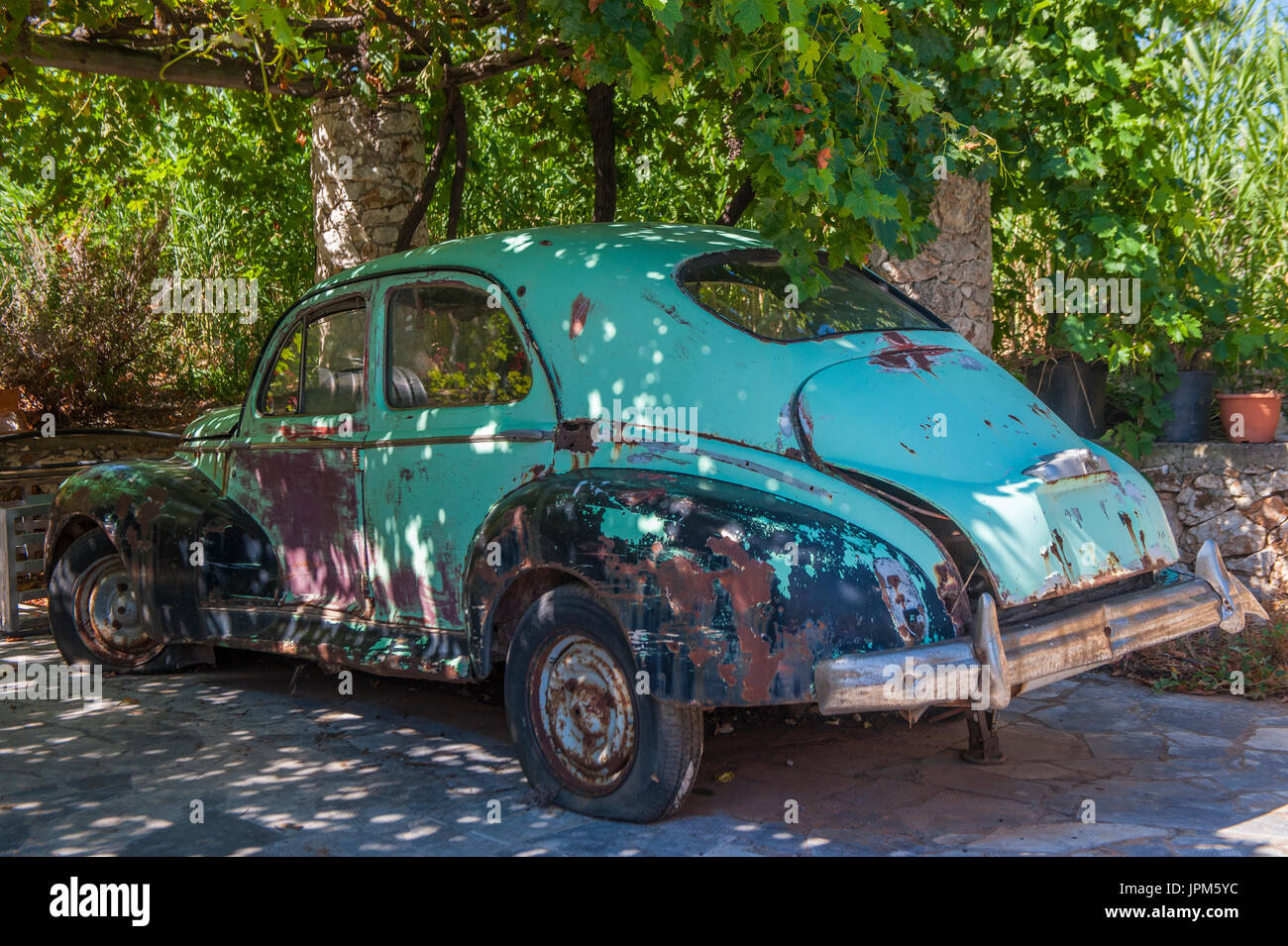 An old Peugeot car under a canopy of vines in a Mediterranean country Stock Photo
