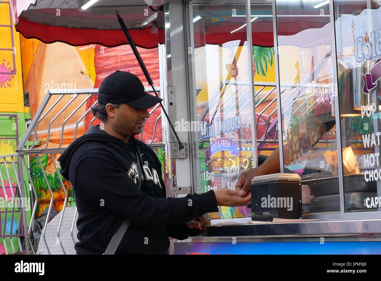 People buying donuts and paying cash at the West Coast Amusements Carnival Stock Photo