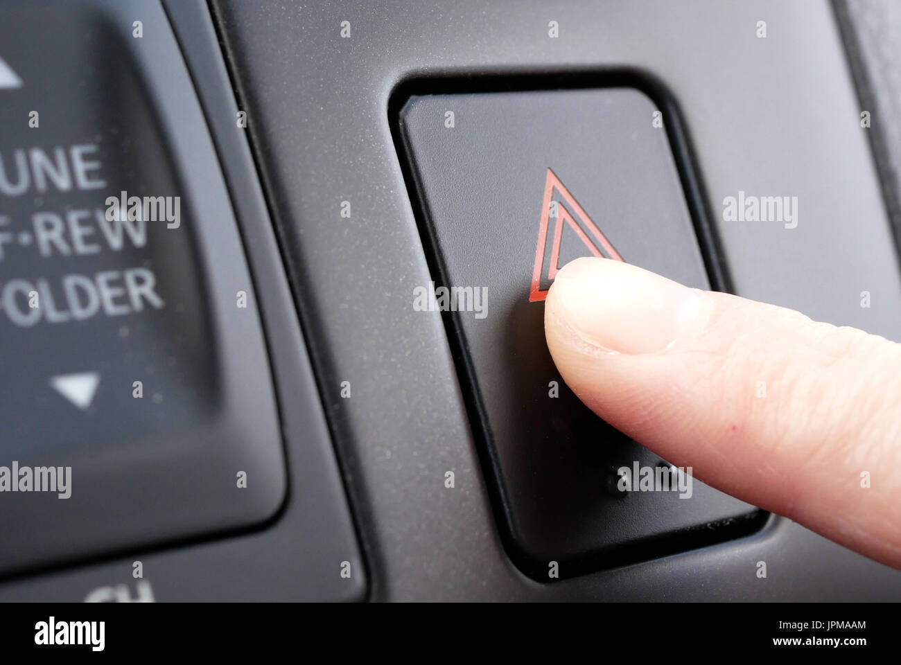 A woman's hand presses the emergency button on car dashboard Stock Photo