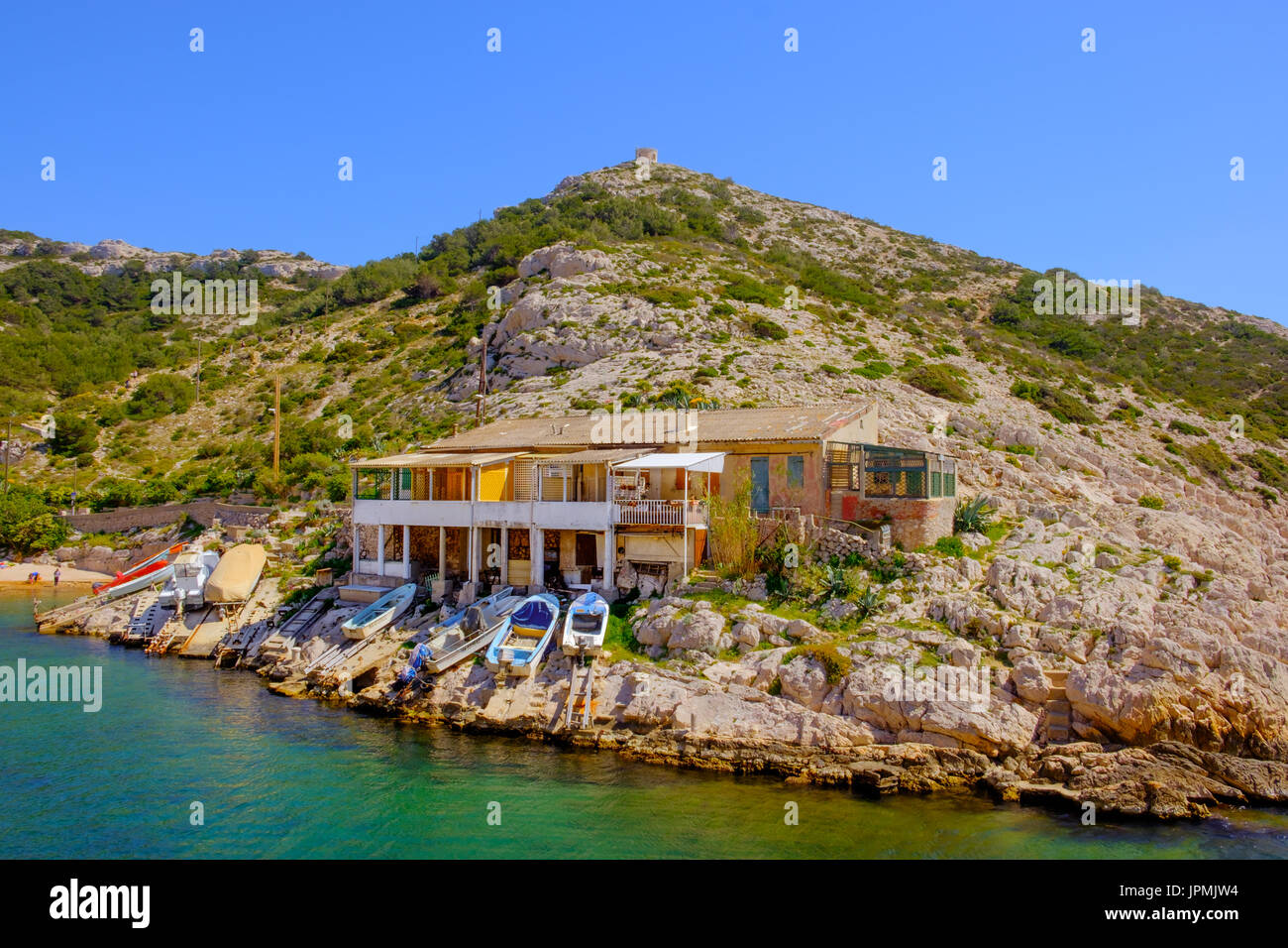 Building and small boats at “Les Goudes” one of Marseilles quarter in the 8th district by the Marseilleveyre mountain range and the Mediterranean Sea Stock Photo