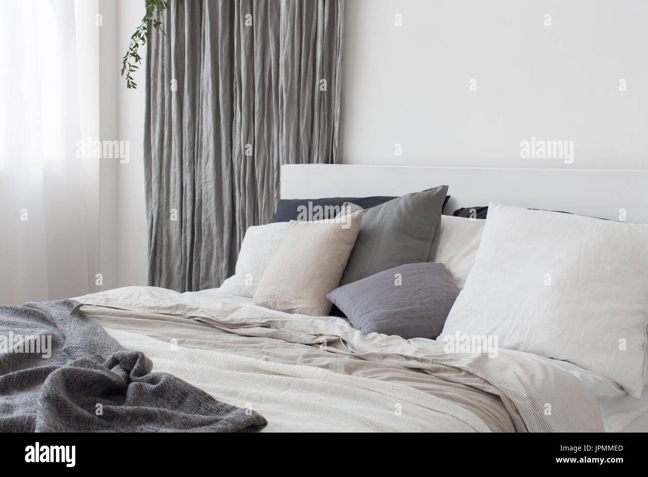 Bed with white and grey linens Stock Photo