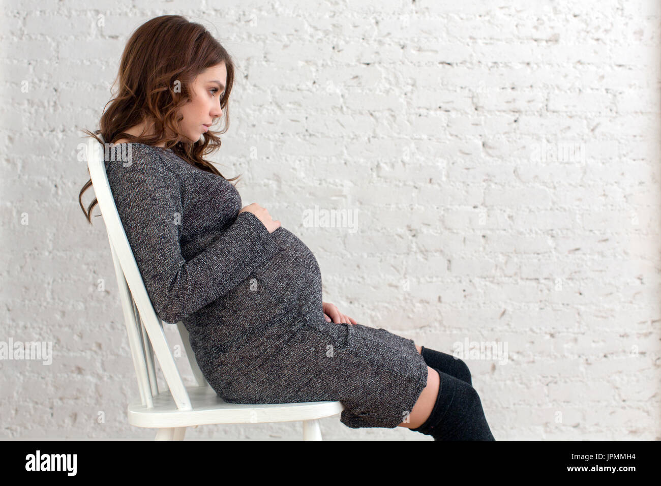 Pregnant female sitting on chair posing Stock Photo