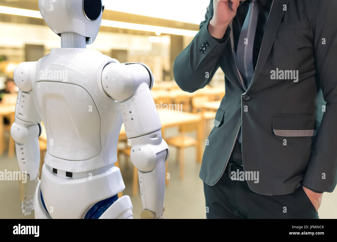 Artificial intelligence , ai concept. Businessman suit use self-driving robot assistant , robo-advisor in library to search for books. Stock Photo