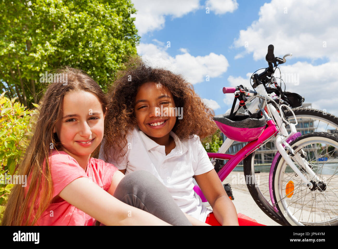 Girl friends resting after cycling in summer city Stock Photo