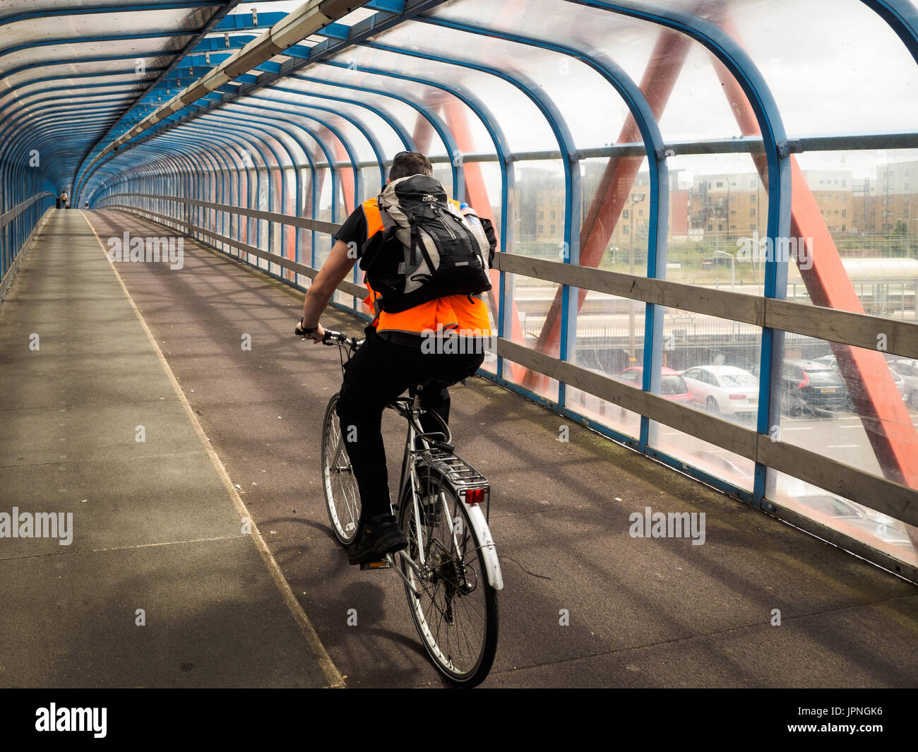 Cycling Bridge. Cyclist rides across the Tony Carter bridge, a cycle and pedestrian bridge crossing the main railway line in Cambridge UK Stock Photo