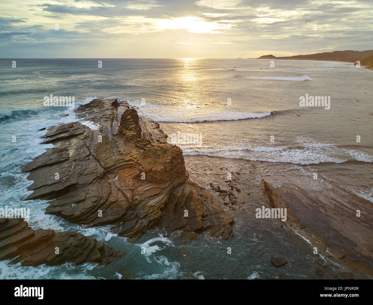 Surfers do it surf in sunset time in Nicaragua. Surfers next to big rock Stock Photo