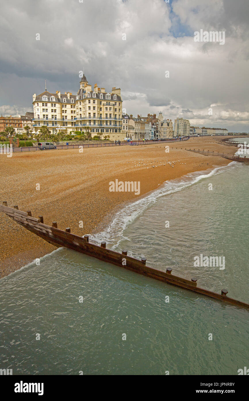 Deserted beach, turquoise water of ocean, and row of waterfront hotels and guesthouses at English holiday destination of Eastbourne Stock Photo