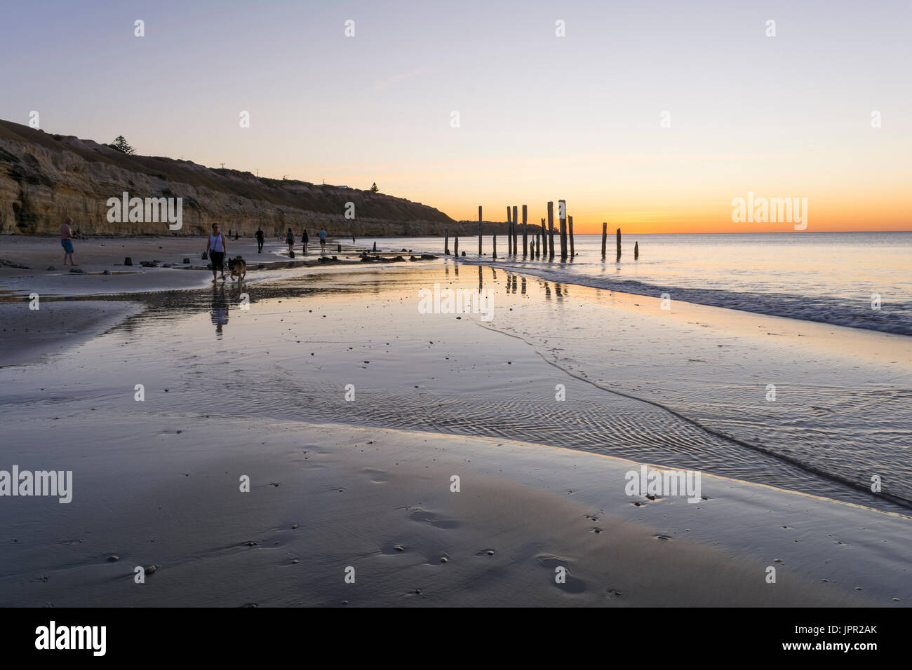 PORT WILLUNGA BEACH, SOUTH AUSTRALIA / AUSTRALIA - DECEMBER 15, 2015: People walking on the beach, enjoying the sunset and view of the old jetty ruins Stock Photo