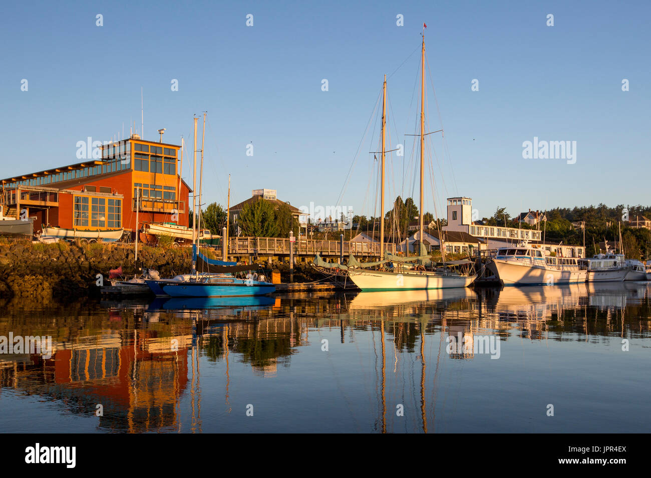 Port Townsend marina at Point Hudson with schooner sailing boat Martha during sunrise. Northwest Maritime Center in background. Stock Photo