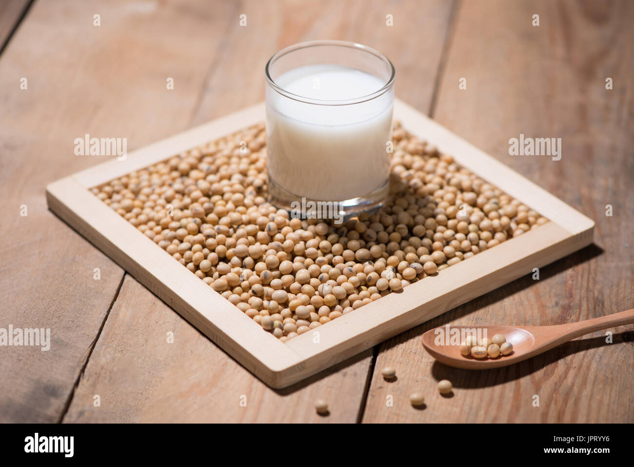 Soy milk or soya milk and soy beans in spoon on wooden table. Stock Photo