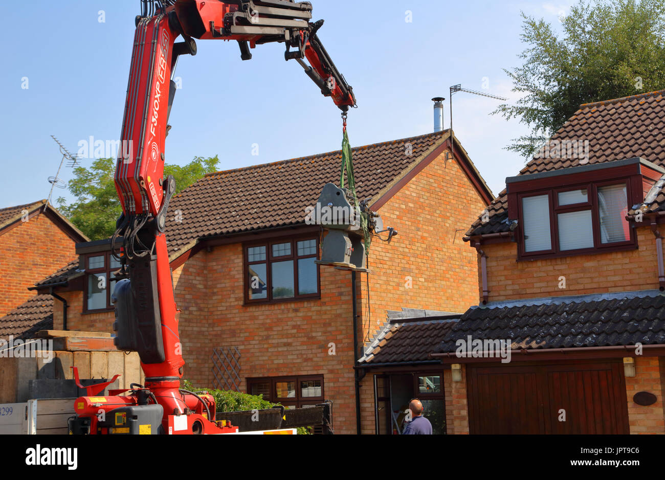 And out she comes, a large Henry Milnes Lathe is lifted from the rear of a property out througha gap between houses to the waiting lorry for transport Stock Photo