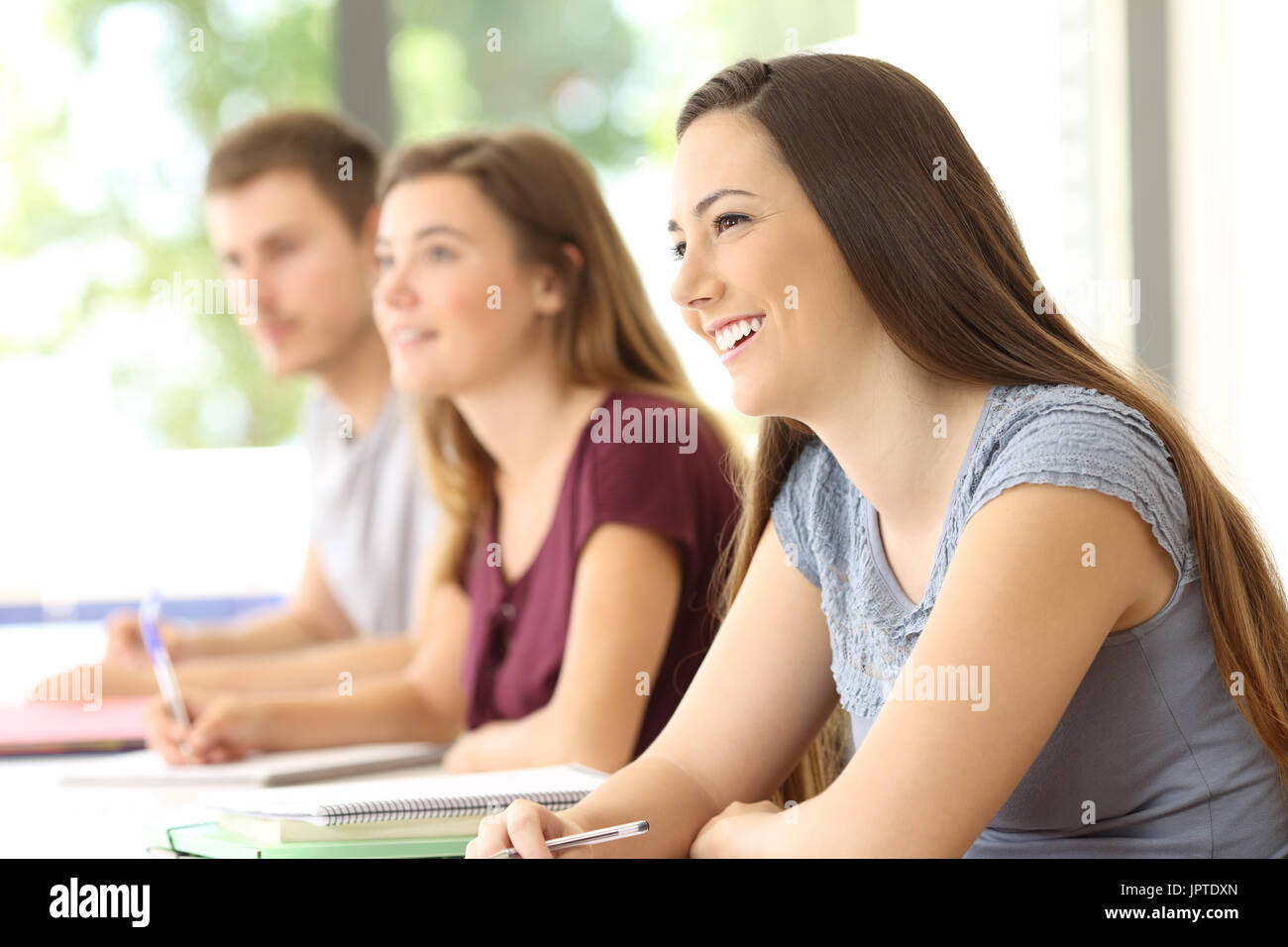 Three attentive students listening to a lesson in a classroom Stock Photo