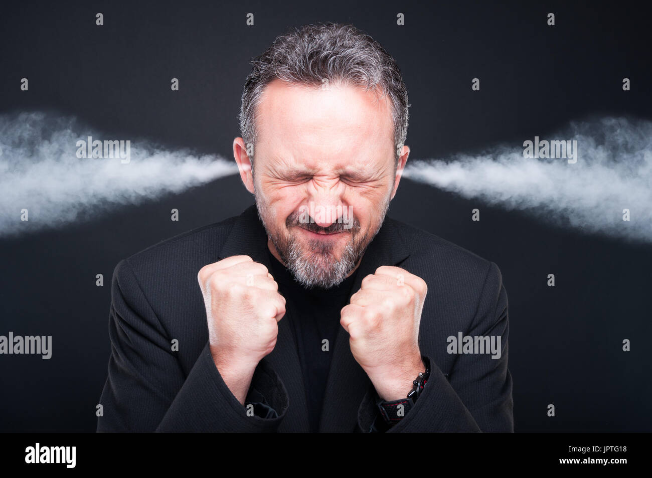 Angry frustrated man with exploding head and steam coming out of his ears on dark background Stock Photo