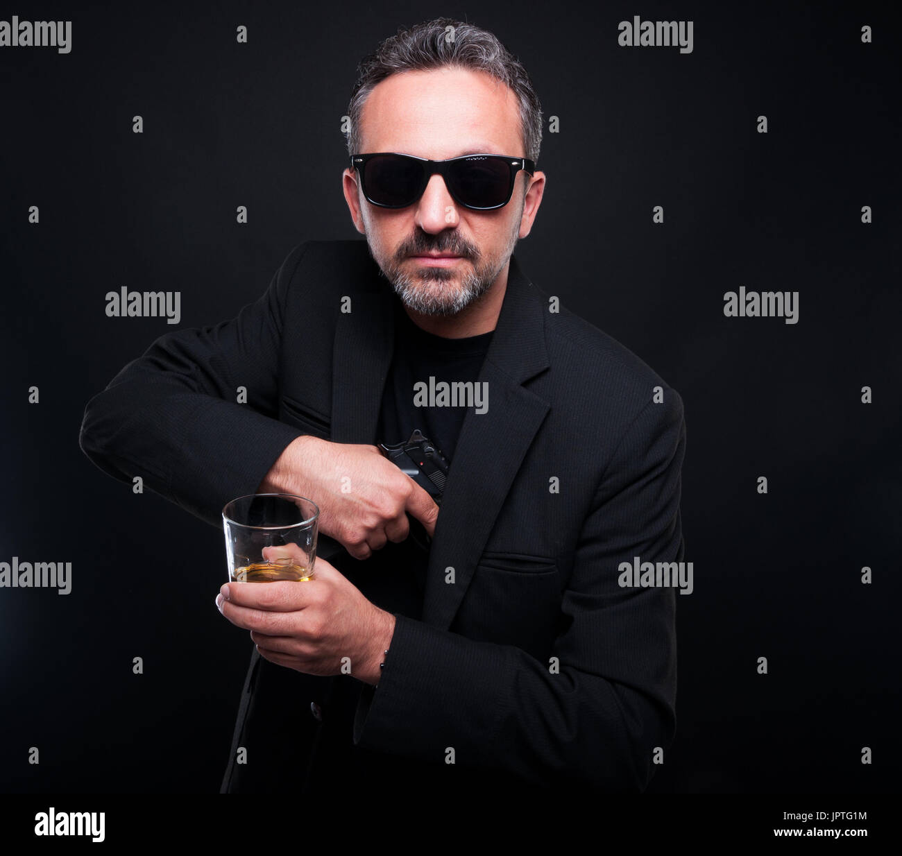 Male gangster removing his gun from jacket pocket while he is drinking