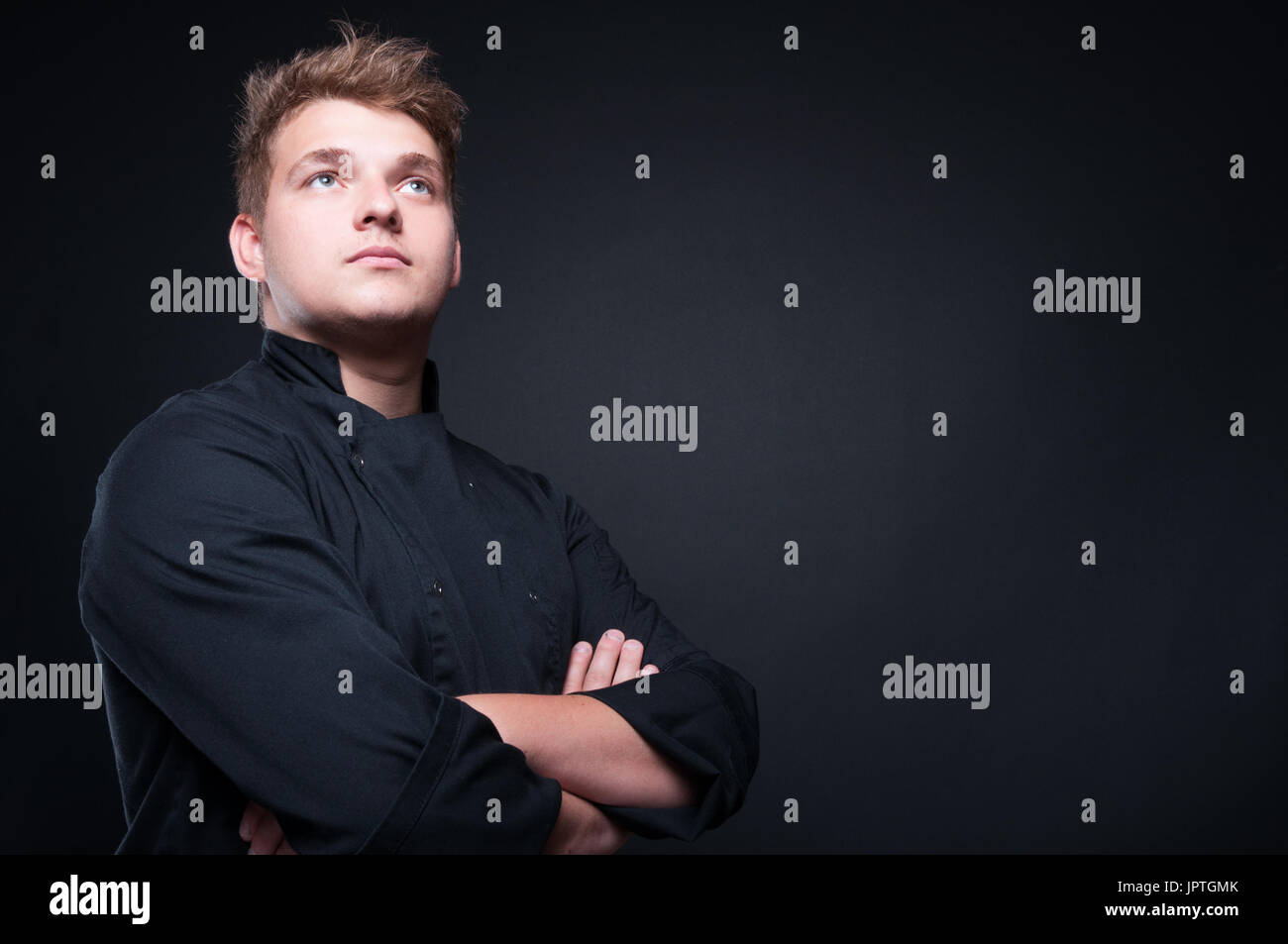 Low angle shot of talented male chef looking away isolated on black bakground Stock Photo