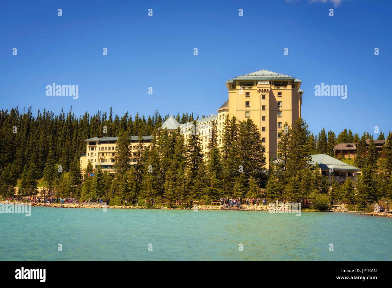 Many tourists enjoying a sunny day at the Fairmont Chateau Lake Louise in canadian Rocky Mountains. Stock Photo