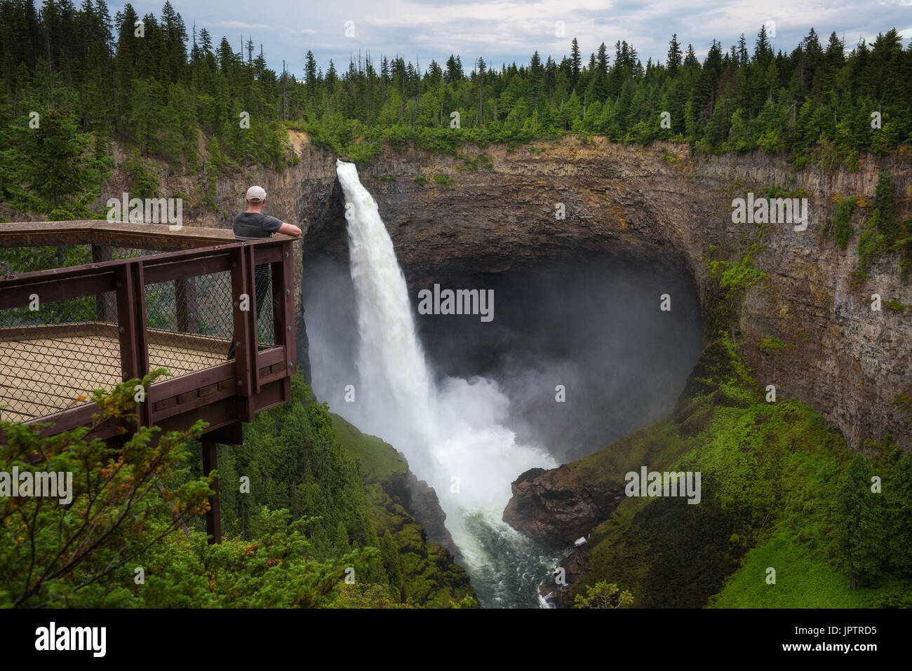 Tourist standing on an outlook platform and looking at the Helmcken Falls in Wells Gray Provincial Park near Clearwater, Canada. Stock Photo