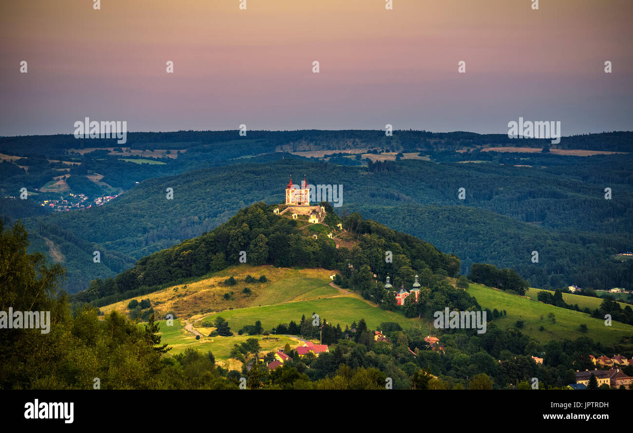 Upper church with two towers and baroque calvary in Banska Stiavnica, Slovaka at sunset. Banska Stiavnica is a completely preserved medieval town and  Stock Photo