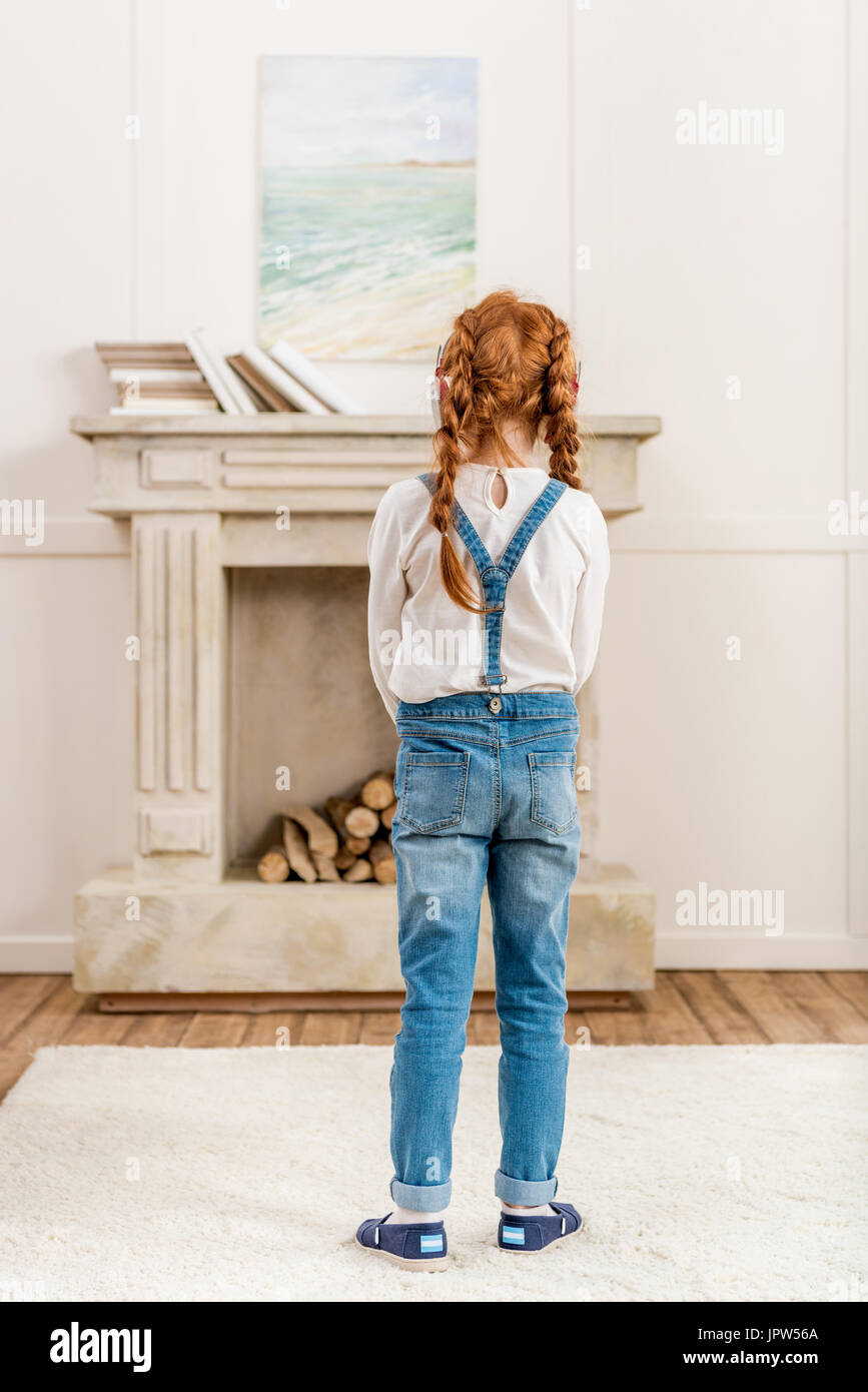 back view of little girl looking at picture on wall at home Stock Photo