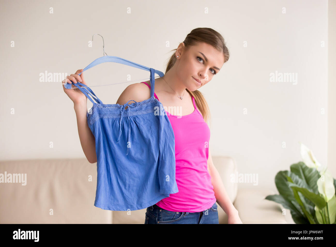 Pensive lady standing with blouse on hanger Stock Photo