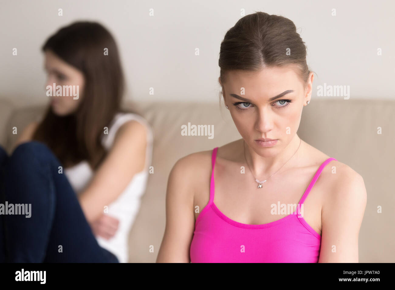 Grumpy woman sitting next to offended girlfriend Stock Photo