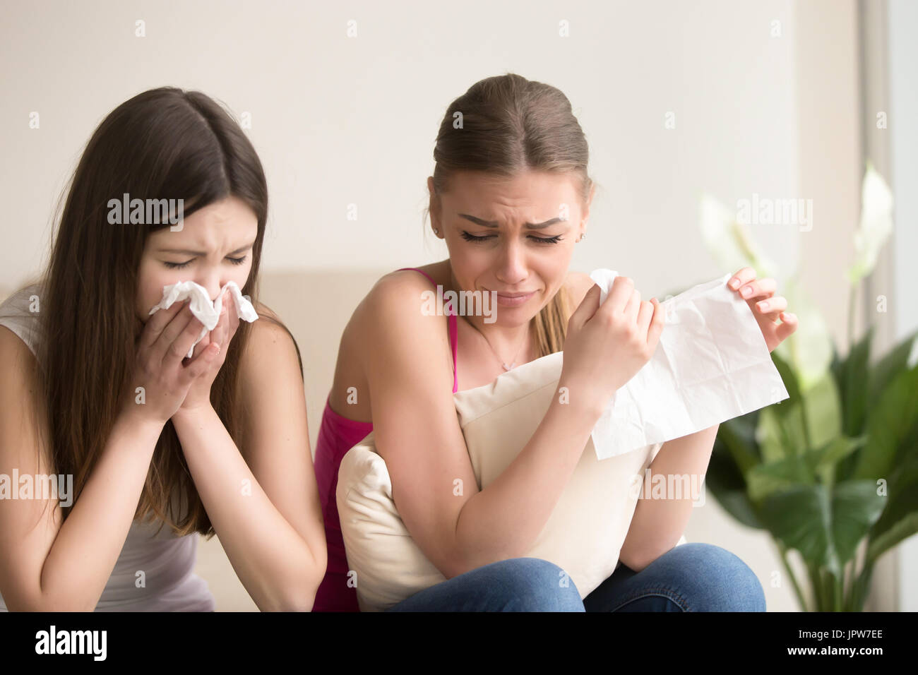 Two young women friends crying together at home Stock Photo
