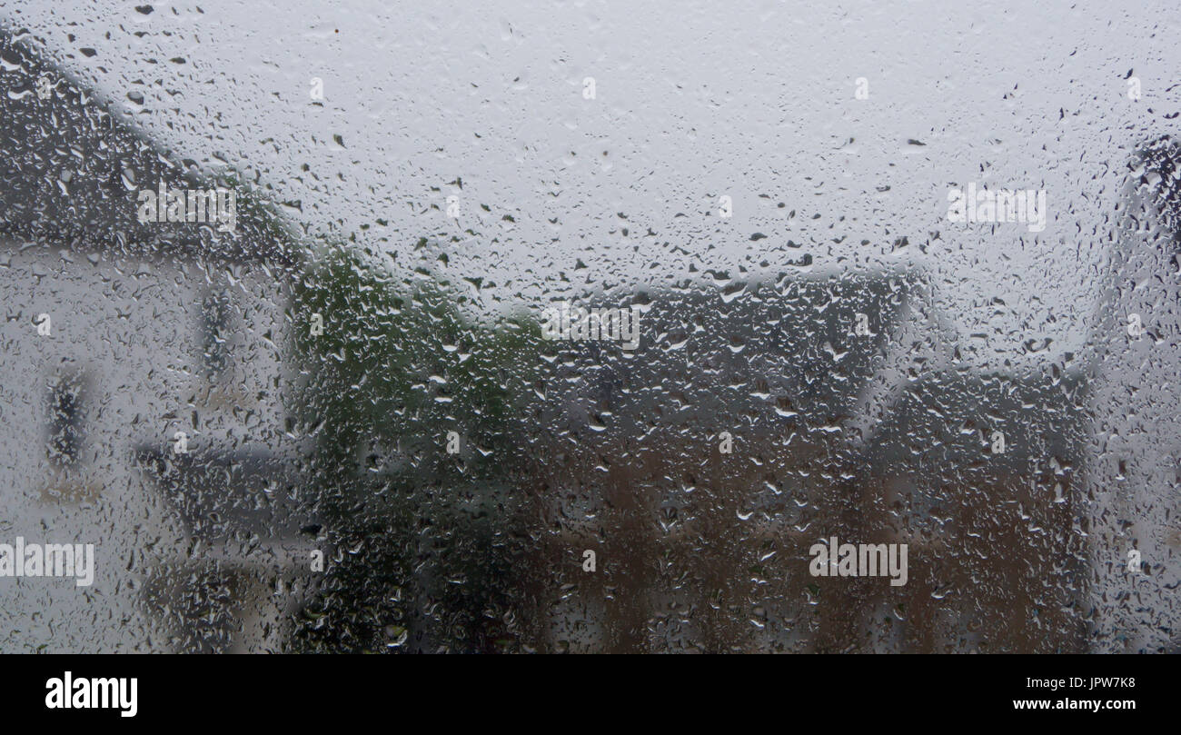 Looking through a raindrop covered window at houses on a rainy summers day Stock Photo