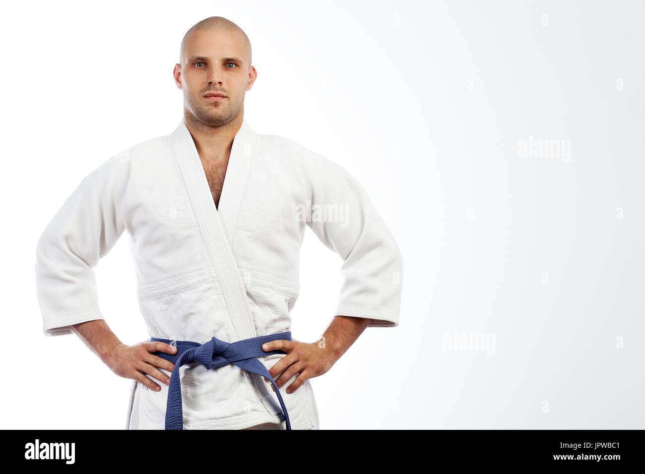 A young strong man in a white kimono for sambo, jiu jitsu and other martial  arts with a blue belt posing on white isolated background, hands holding o  Stock Photo - Alamy