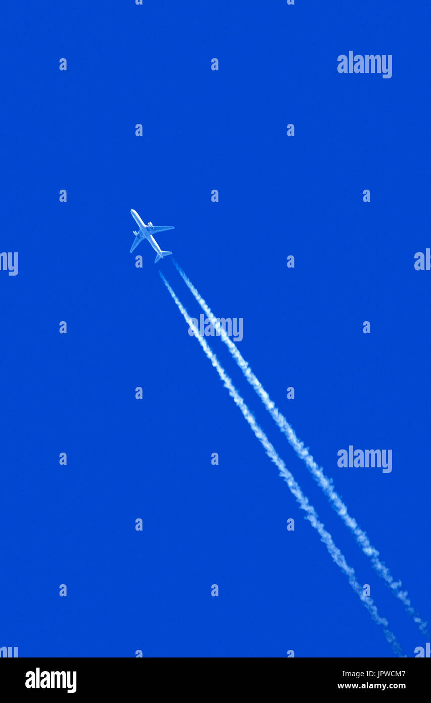 Boeing 767 making contrail vapour trail against blue-sky Stock Photo