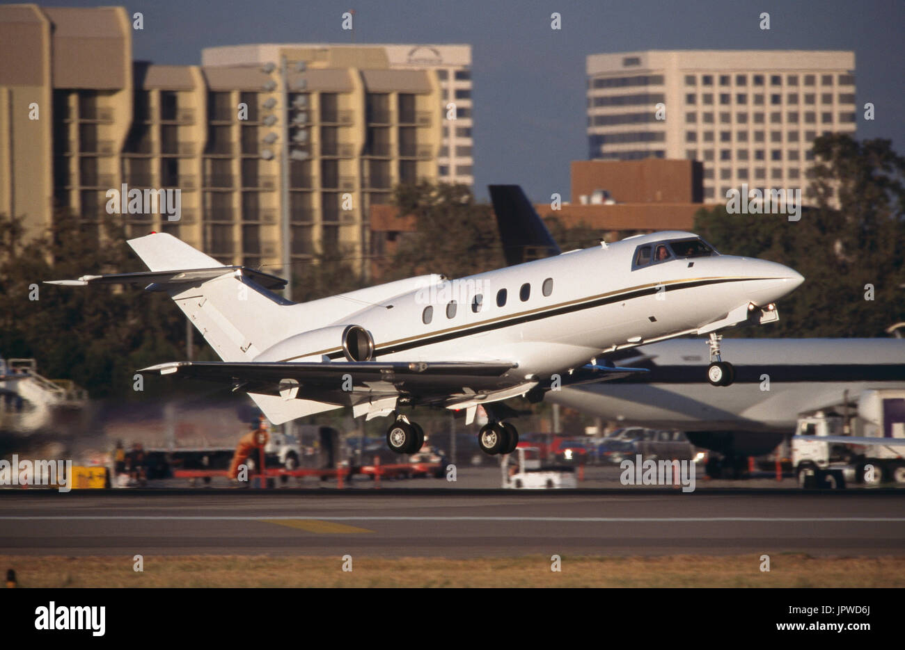 Hawker 800 business-jet taking-off with office-buildings behind Stock Photo