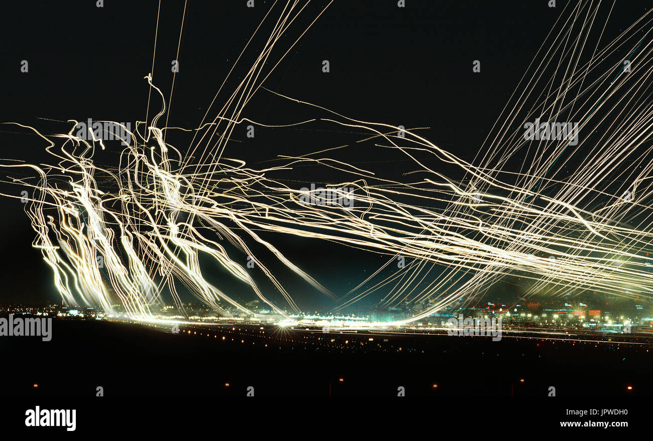 long time and multiple exposure image of aircraft lights during take-offs, final-approach and landings during the night making streaks of light over L Stock Photo