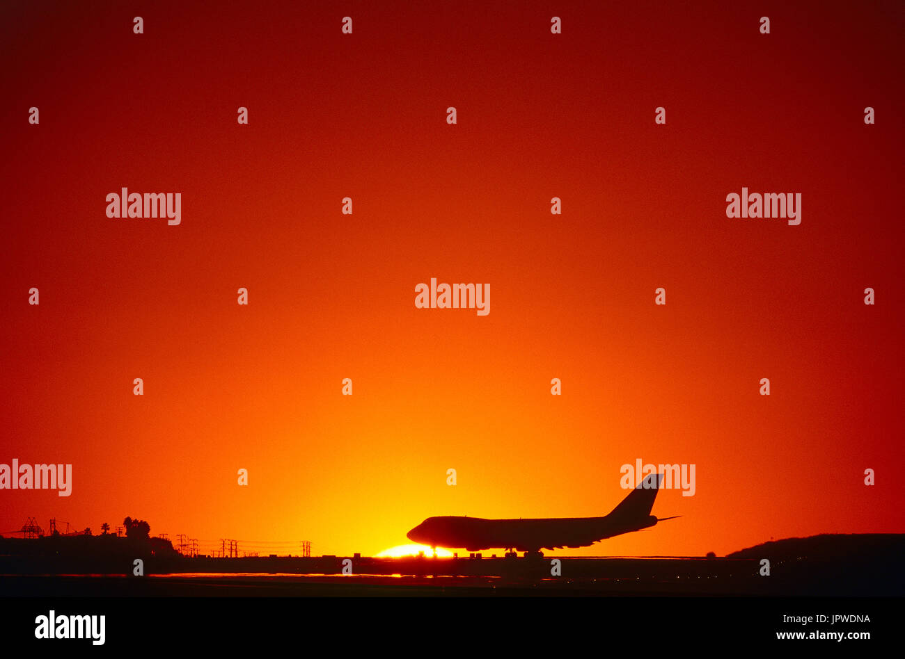 Boeing 747 taxiing under an orange sky at sunset Stock Photo