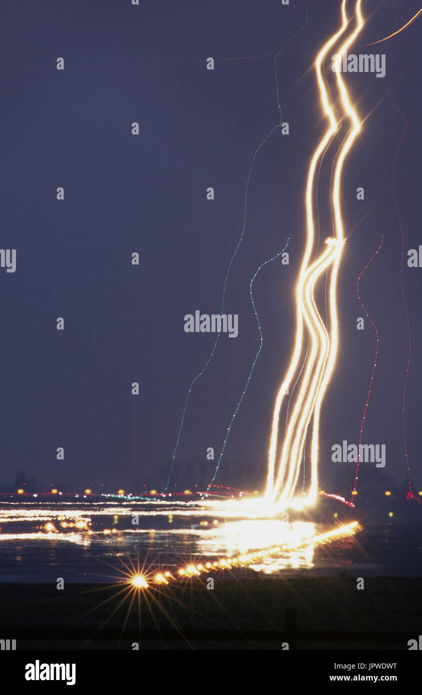several airliners lights at night on final-approach and landing on the runway with runway lights during a long time exposure Stock Photo