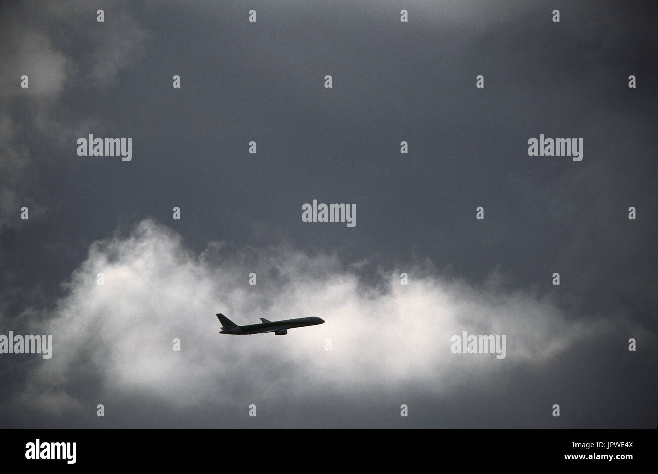 Boeing 757-200 climbing enroute amongst dark clouds Stock Photo
