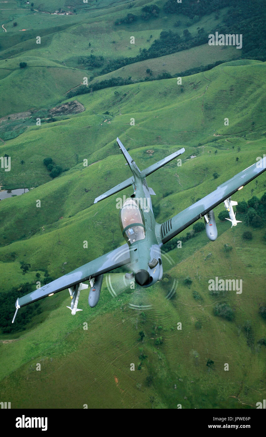 Brazilian Air Force Embraer EMB-314 Super Tucano banking over fields and trees Stock Photo