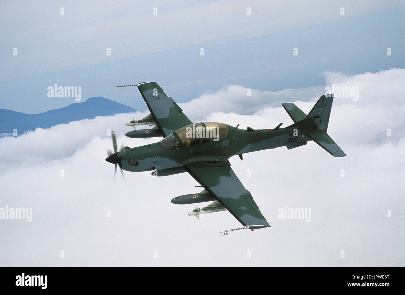 Brazilian Air Force Embraer EMB-314 Super Tucano banking over clouds and hills Stock Photo