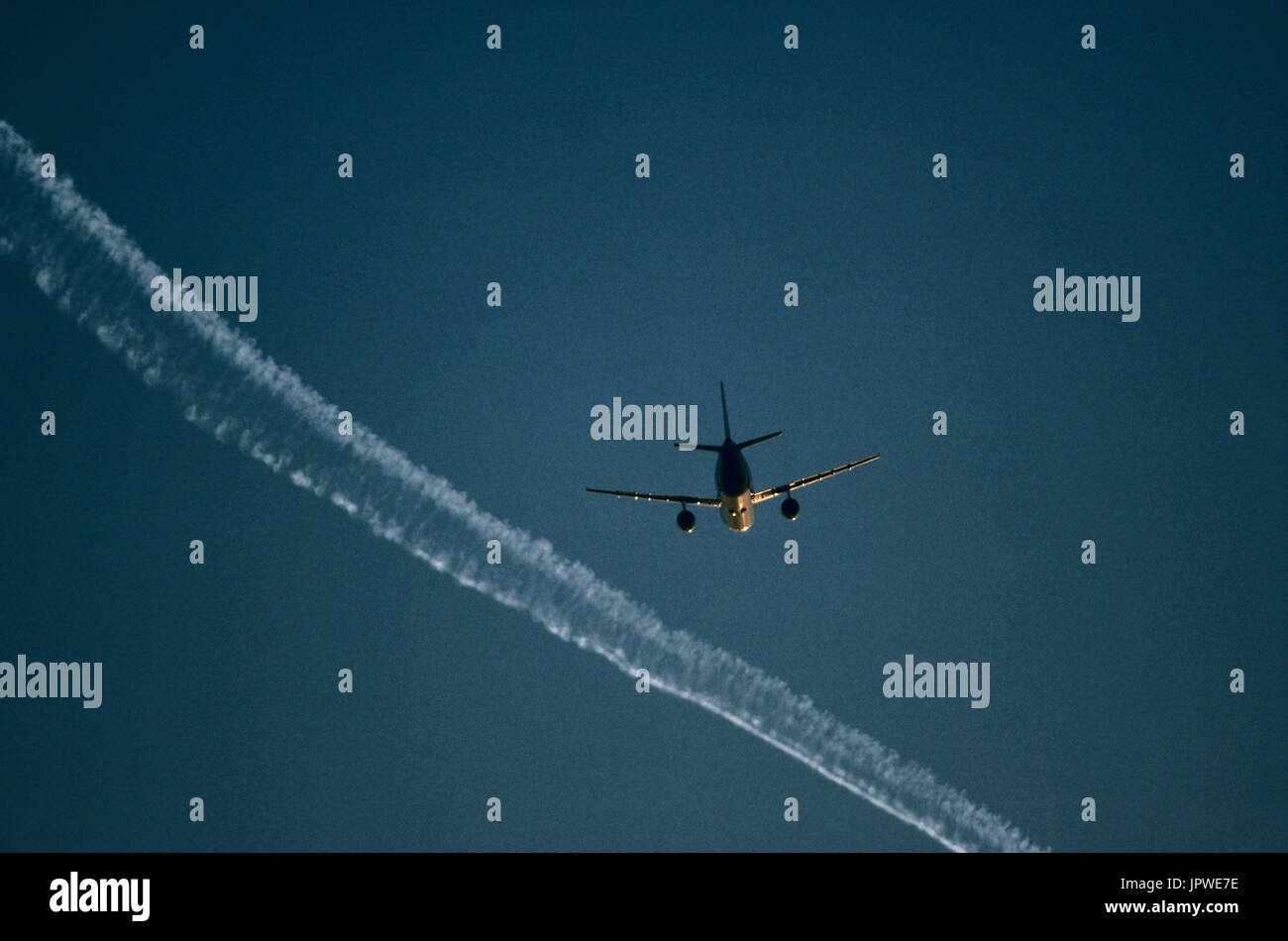 Boeing 757-200 flying enroute with an airliner contrail above at dusk Stock Photo