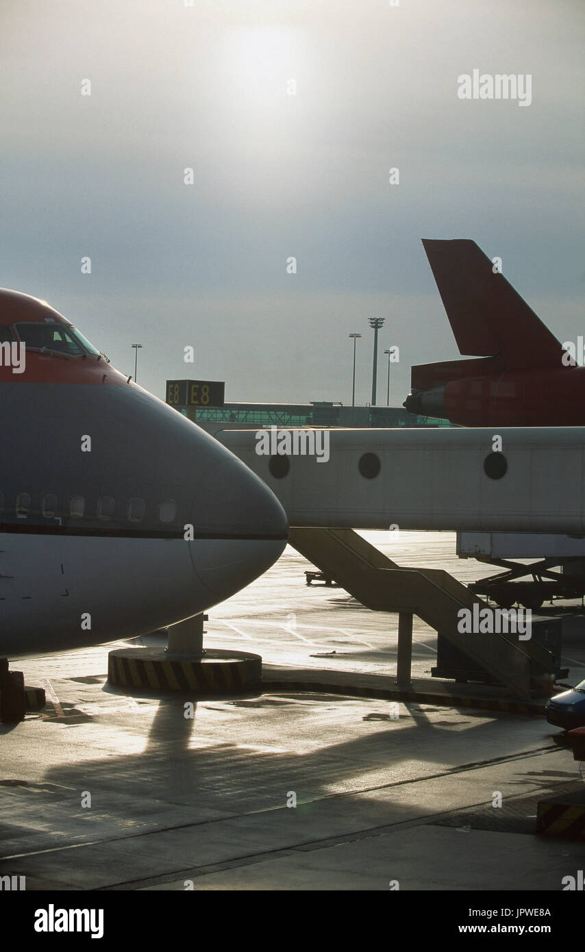 generic Boeing 747 parked at Gate E8 with ground control-tower and jetway with McDonnell Douglas DC-10 tail behind Stock Photo