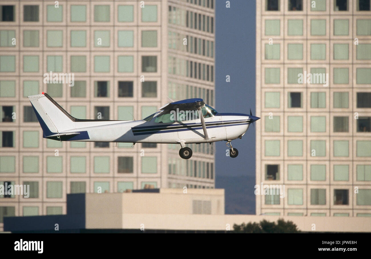 generic Cessna 172N Skyhawk climbing out after take-off flying past an office building Stock Photo