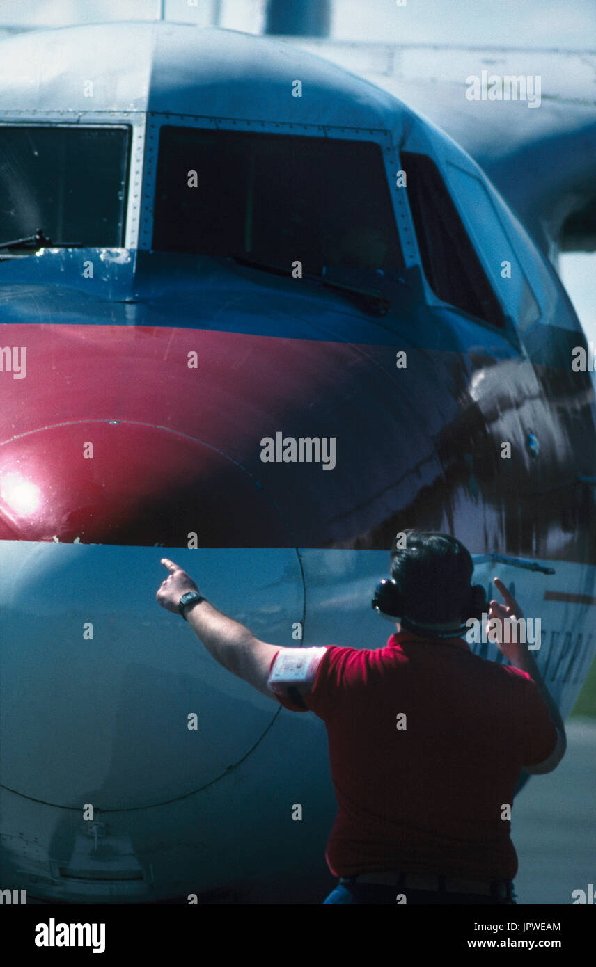 marshaller with ear defenders signalling to pilot to start engines on a USAir Express DHC-7 Dash 7 Stock Photo