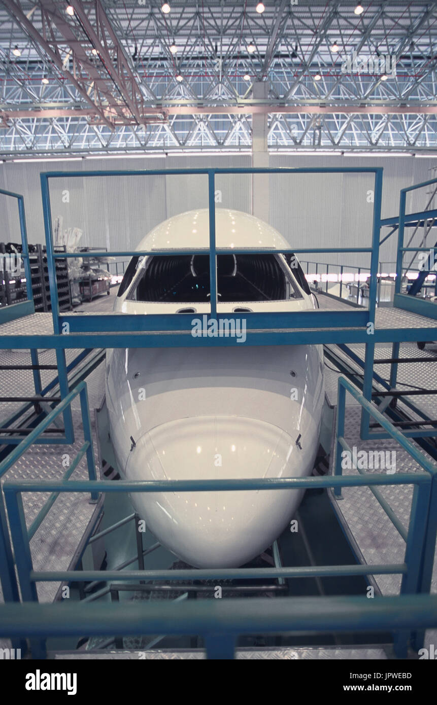 Embraer 170 fuselage barrel on the factory production-line surrounded by platforms with the hangar ceiling and roof structure above and behind Stock Photo