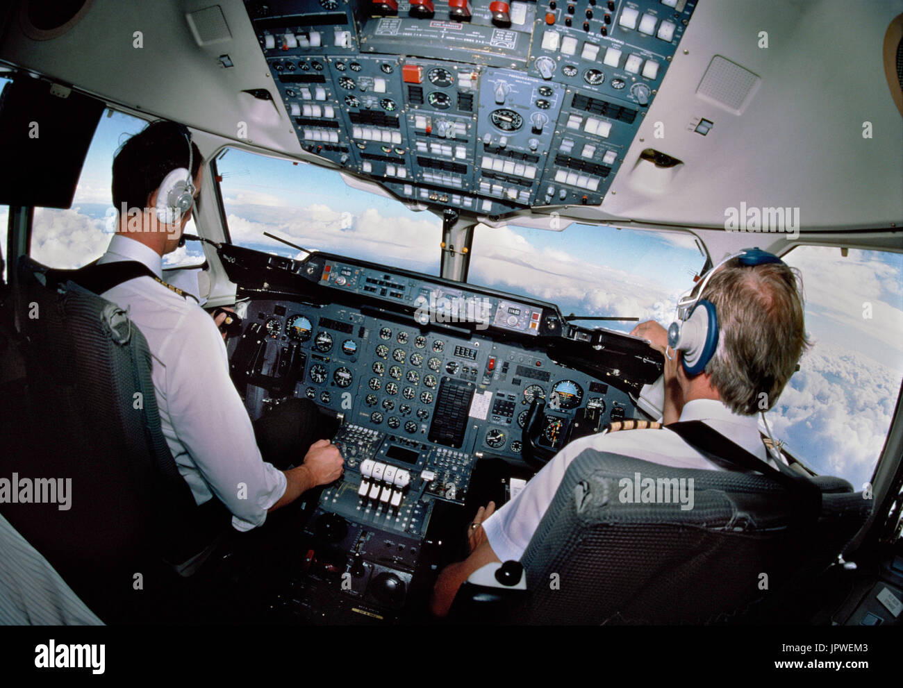 pilots wearing headsets in the cockpit of a BAE 146 flying Stock Photo