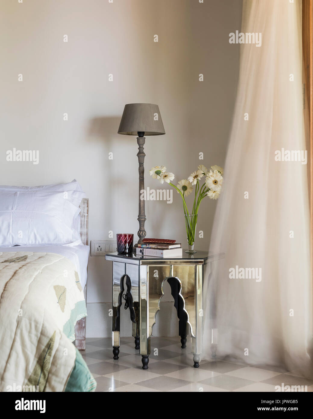 Lamp and flowers on mirrored bedside table Stock Photo Alamy