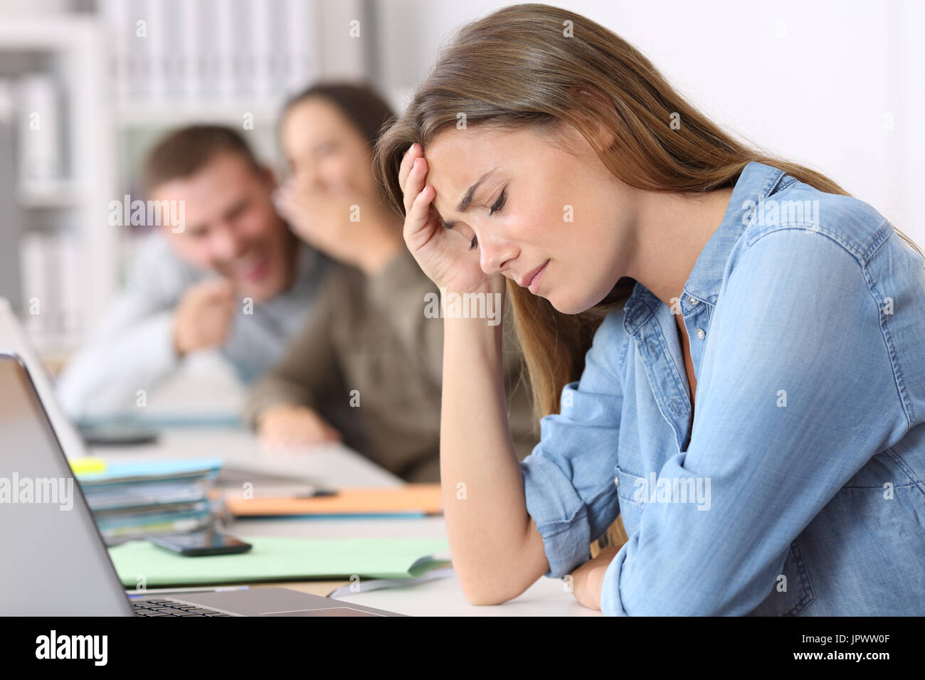 Side view portrait of a bullying victim being criticized at office Stock Photo