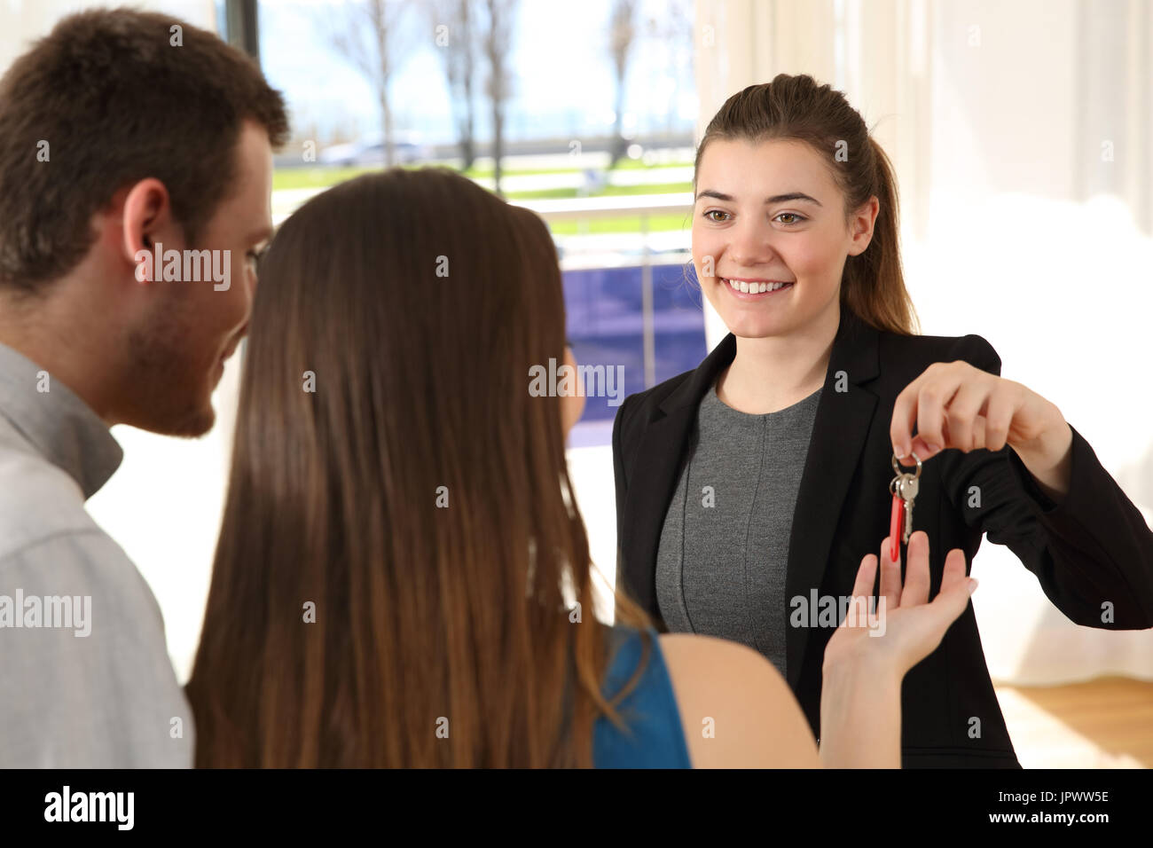 Real estate agent giving home keys after a sale in a house interior